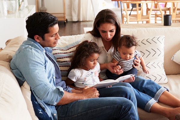 Young Family With Baby Reading A Book Together