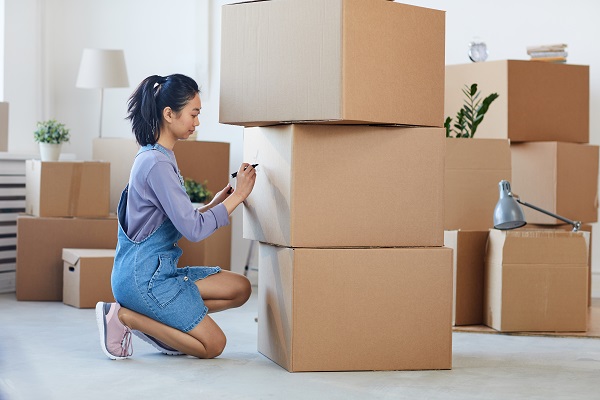Woman Moving Home Writing On Boxes