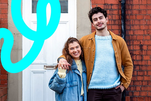 Couple Standing At Front Door Hugging