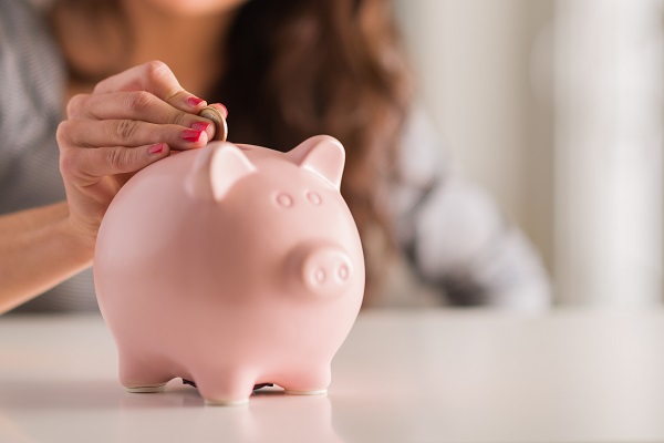 Woman Putting Money In Piggy Bank
