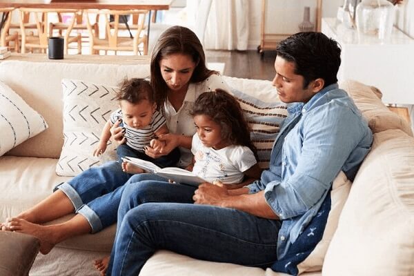 Young Family On Sofa Reading A Book