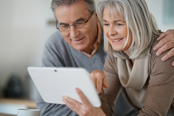 Retired Couple Looking At Ipad Smiling