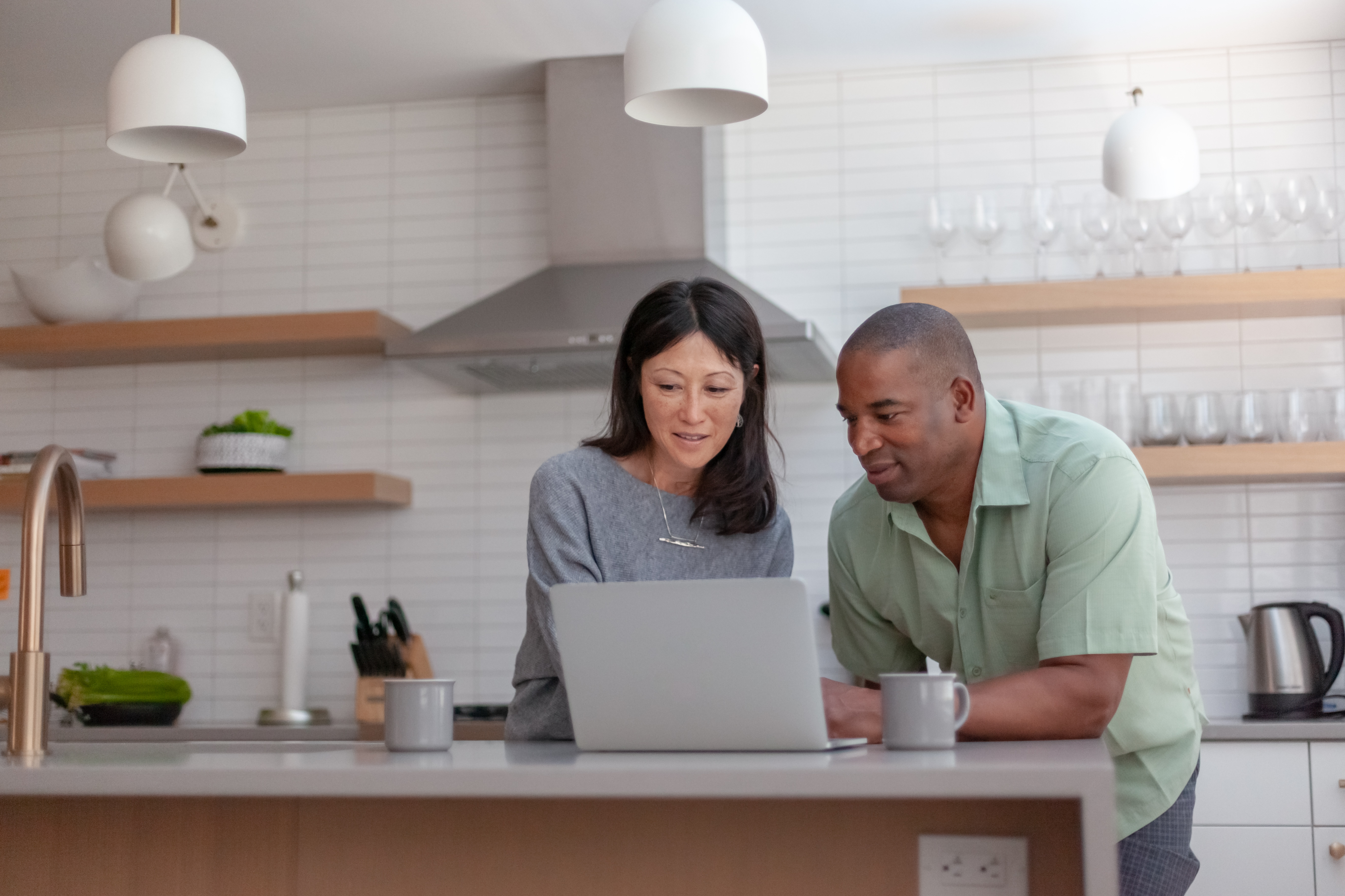 Couple In Kitchen Looking At Laptop